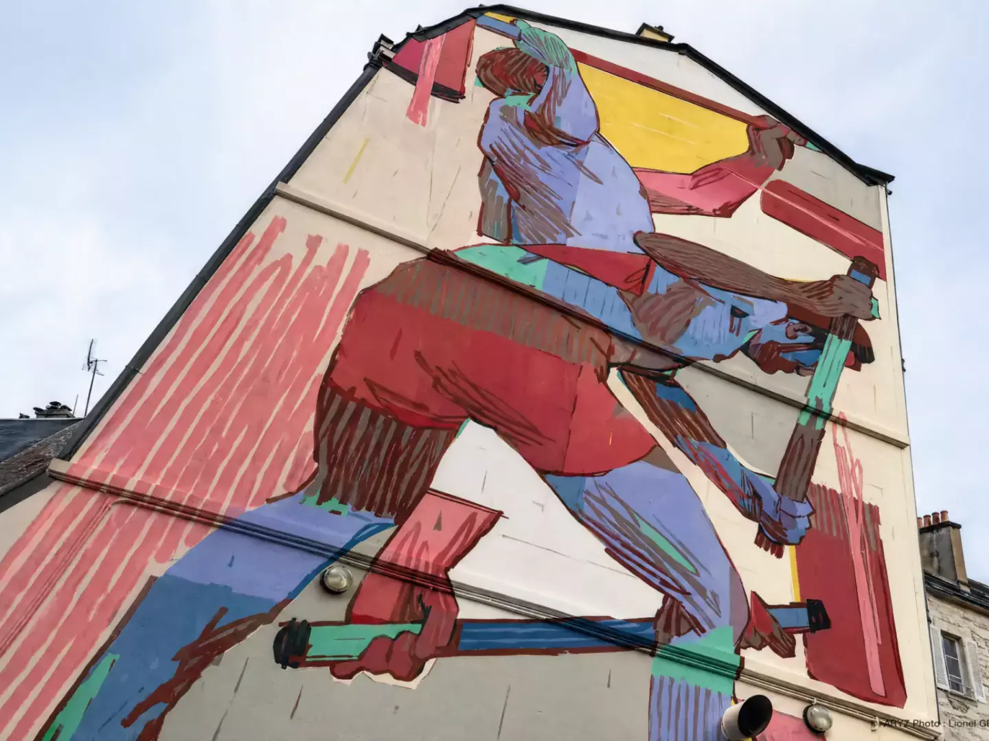 Grande fresque de street art représentant une figure en mouvement sur la façade d’un immeuble.